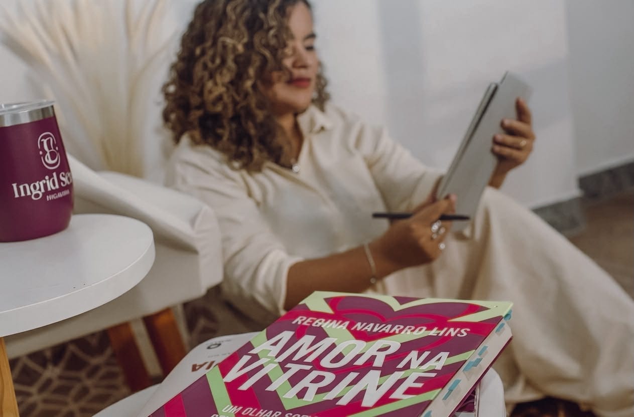 Livros sobre relacionamento e sexualidade ao lado de um copo com a marca de Ingrid Sena