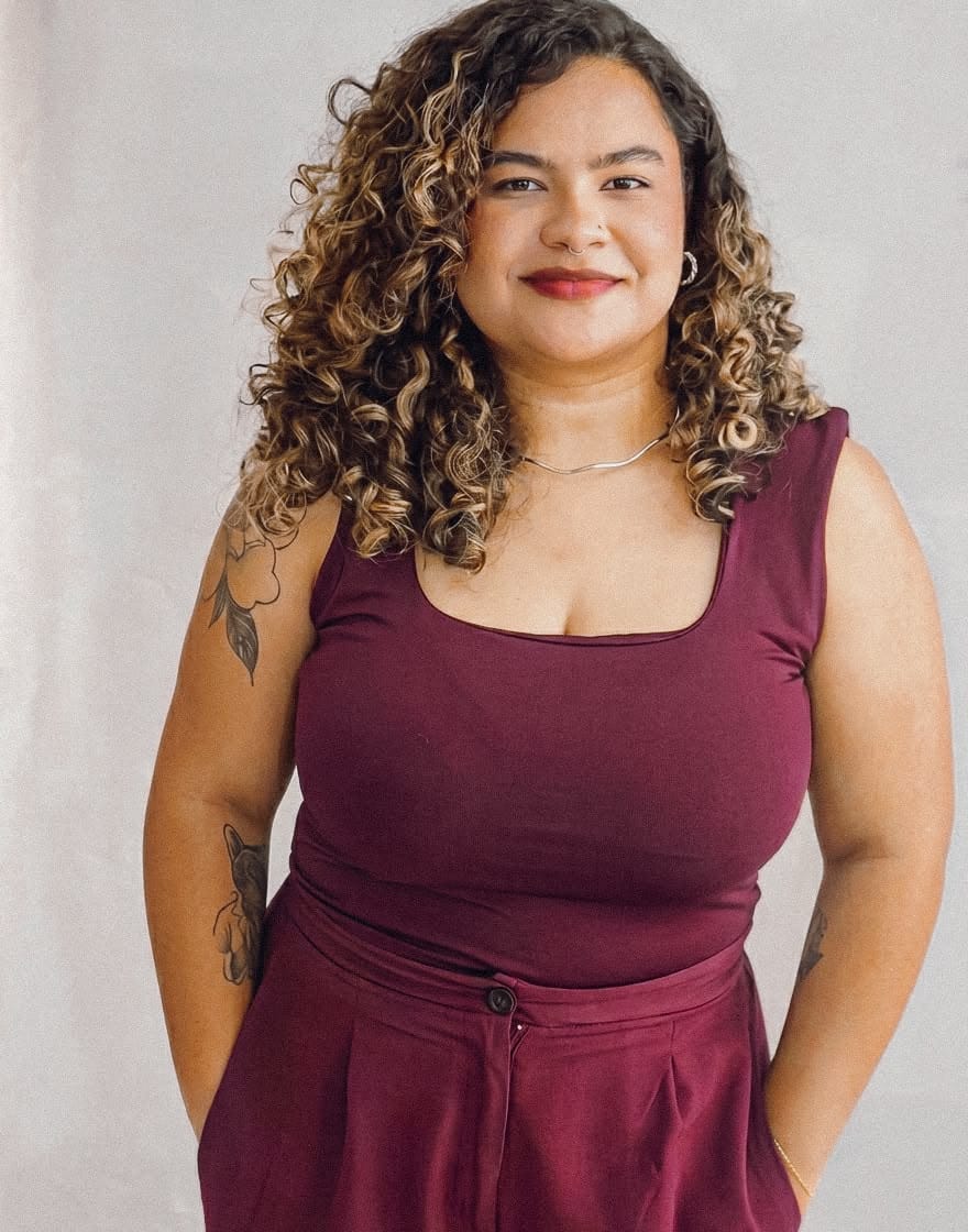 Ingrid Sena, psicóloga, em retrato de frente, sorrindo, sobre fundo claro